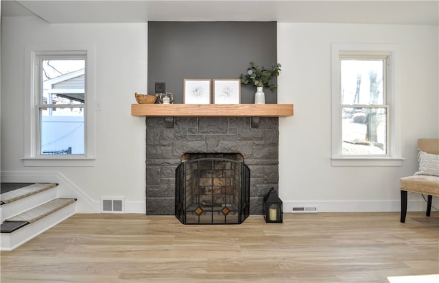 living room with a fireplace, light wood-type flooring, and a healthy amount of sunlight