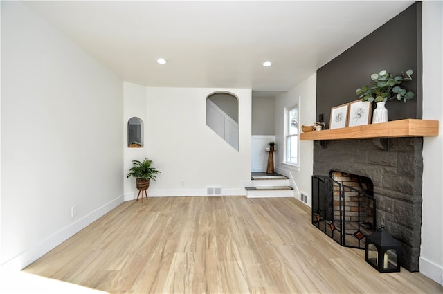 living room with a stone fireplace and light hardwood / wood-style floors