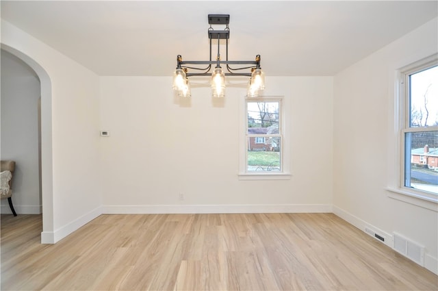 spare room featuring an inviting chandelier and light wood-type flooring