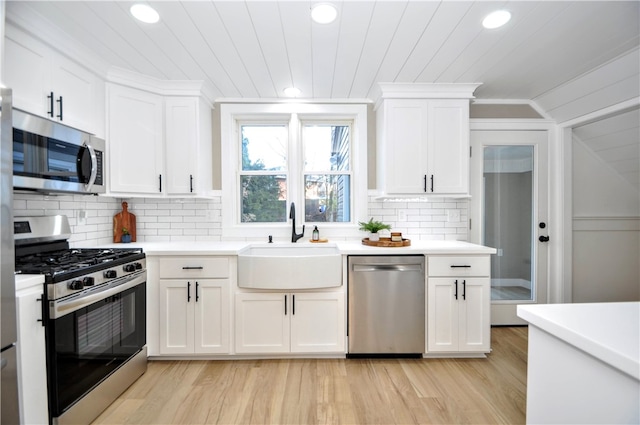 kitchen with white cabinets, sink, vaulted ceiling, light hardwood / wood-style flooring, and stainless steel appliances