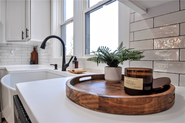 details with tasteful backsplash, white cabinetry, and sink