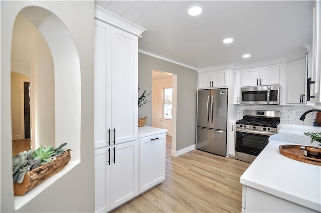 kitchen featuring white cabinets, decorative backsplash, light hardwood / wood-style floors, and appliances with stainless steel finishes