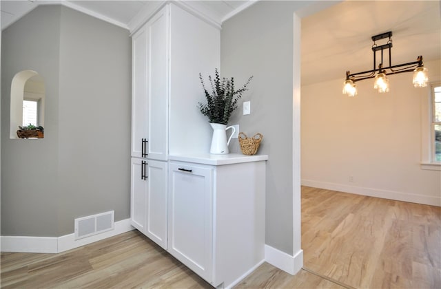 foyer entrance with light hardwood / wood-style floors, an inviting chandelier, and crown molding