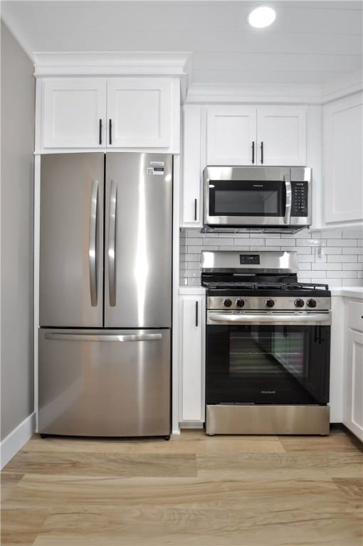 kitchen with white cabinetry, backsplash, appliances with stainless steel finishes, and light hardwood / wood-style flooring