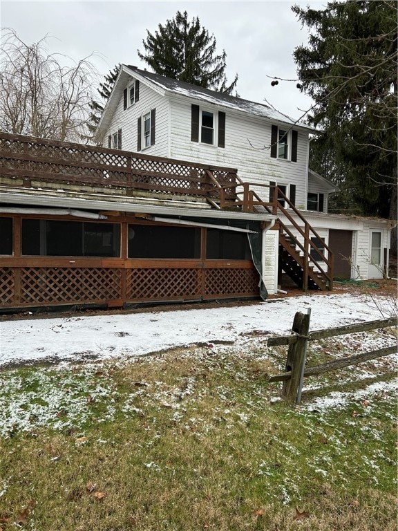 snow covered back of property with a deck