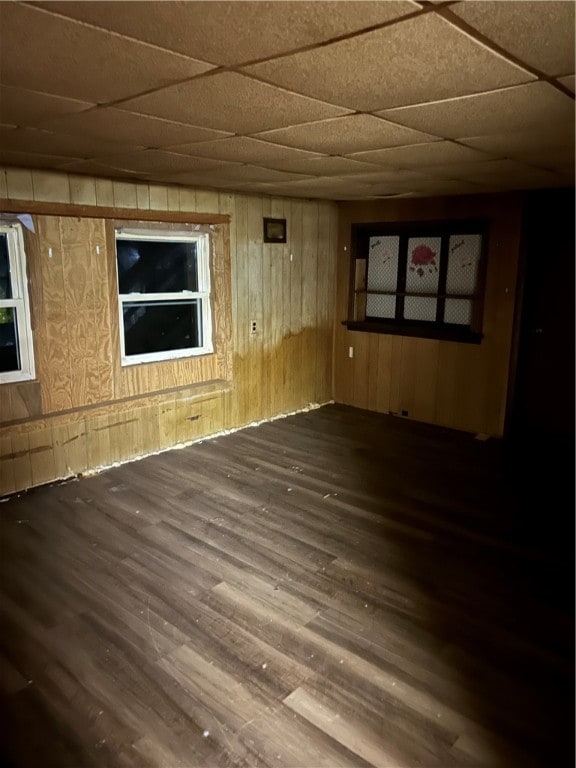 unfurnished room featuring a paneled ceiling, dark hardwood / wood-style floors, and wooden walls