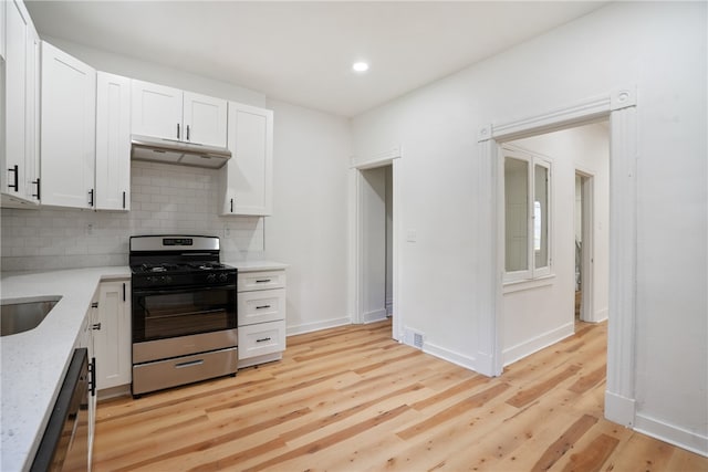 kitchen with light stone countertops, light hardwood / wood-style flooring, white cabinets, and stainless steel appliances