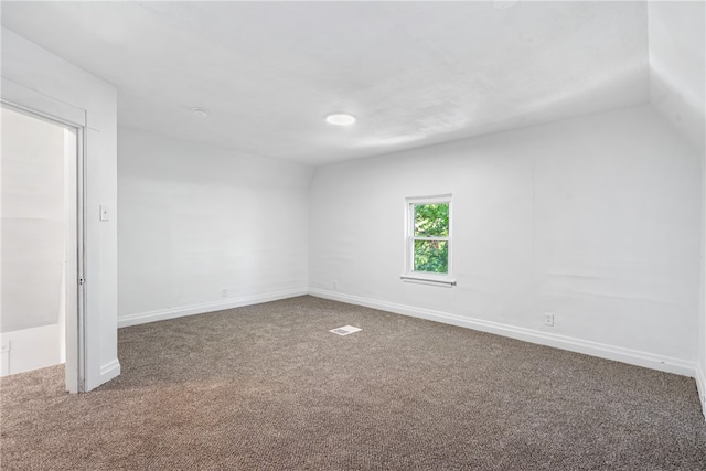 carpeted empty room featuring lofted ceiling