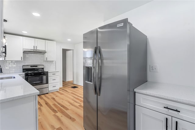 kitchen with white cabinets, sink, light hardwood / wood-style flooring, appliances with stainless steel finishes, and light stone counters