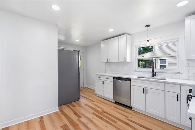 kitchen with sink, white cabinets, stainless steel appliances, and decorative light fixtures