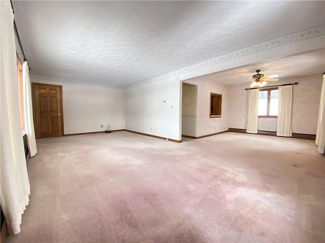 empty room featuring a textured ceiling, light colored carpet, and ceiling fan