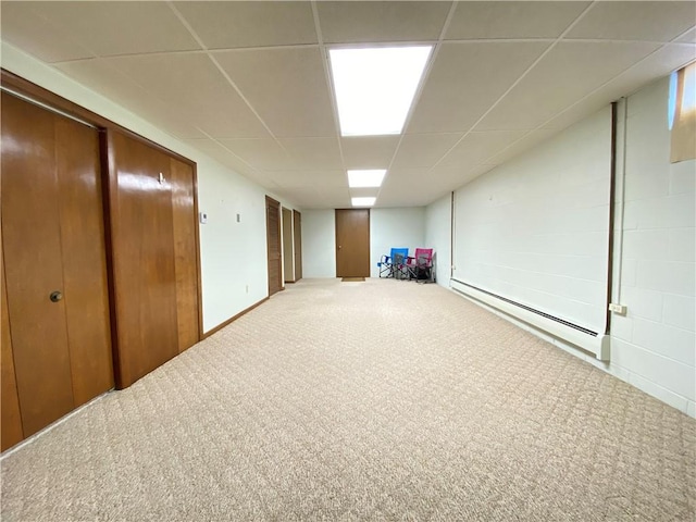 basement featuring a paneled ceiling, carpet floors, and a baseboard radiator