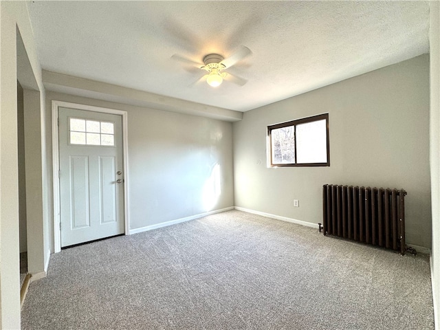 carpeted spare room with a textured ceiling, radiator, and ceiling fan