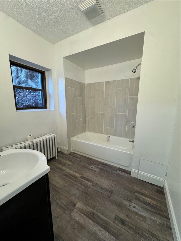 bathroom featuring hardwood / wood-style floors, vanity, radiator heating unit, and a textured ceiling