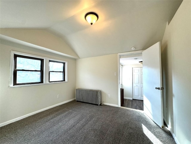 interior space with lofted ceiling, dark carpet, and radiator heating unit