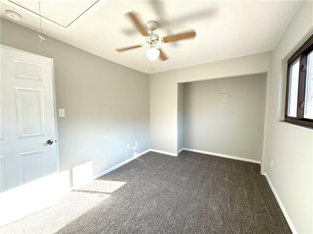 empty room with ceiling fan and dark carpet