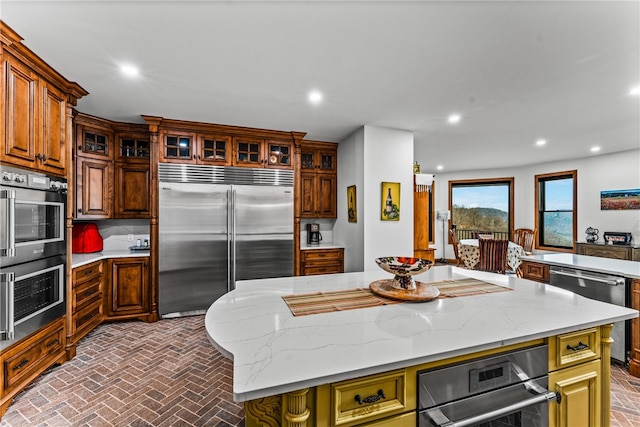 kitchen featuring a breakfast bar area, light stone countertops, a center island, and appliances with stainless steel finishes