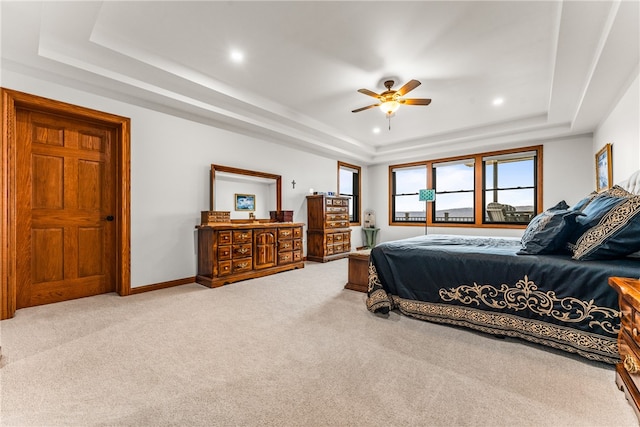 carpeted bedroom with a raised ceiling and ceiling fan