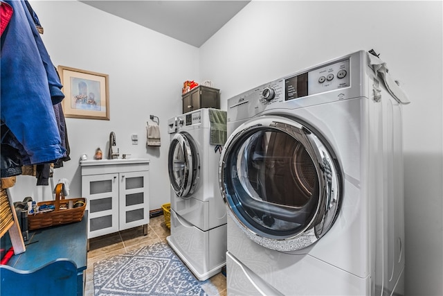 washroom featuring cabinets, washing machine and dryer, light tile patterned floors, and sink