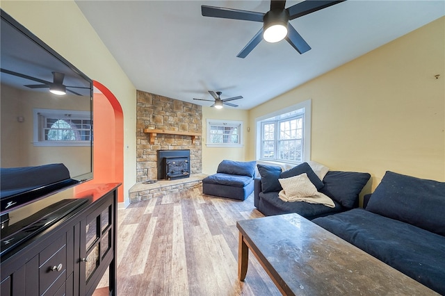 living room with light wood-type flooring, a wood stove, and ceiling fan