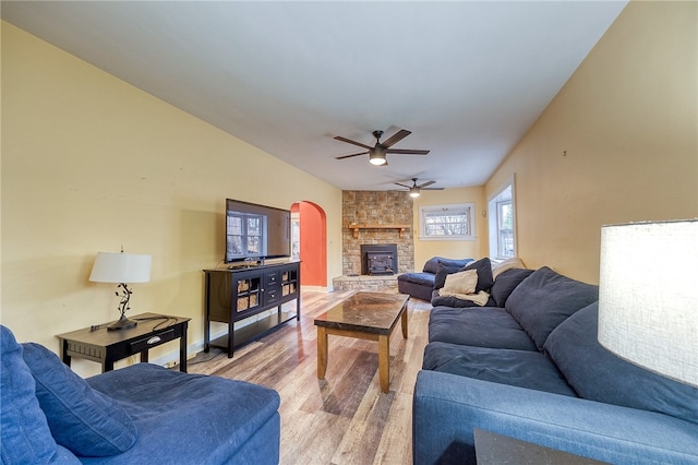 living room with a stone fireplace, ceiling fan, lofted ceiling, and hardwood / wood-style flooring