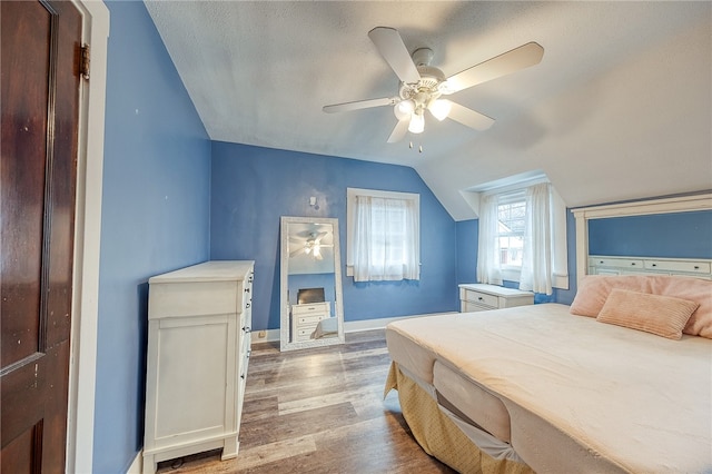 bedroom with ceiling fan, light hardwood / wood-style floors, a textured ceiling, and vaulted ceiling