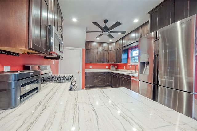 kitchen featuring ceiling fan, sink, stainless steel appliances, light stone counters, and dark brown cabinets