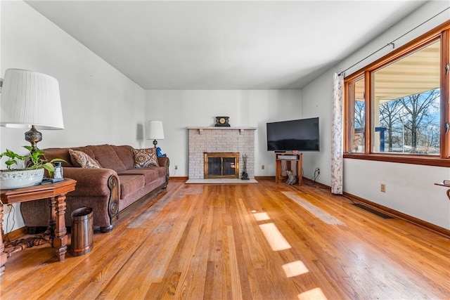 living room featuring light hardwood / wood-style floors and a brick fireplace