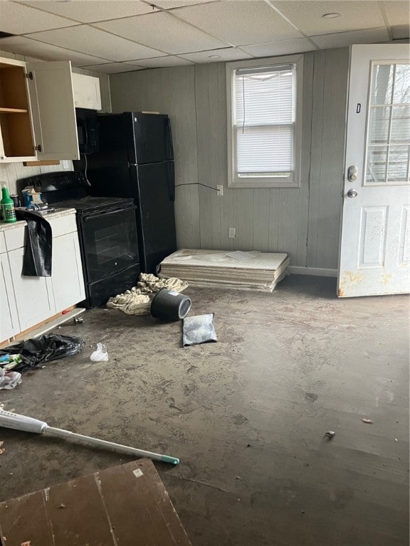 kitchen featuring white cabinets, a drop ceiling, and black appliances