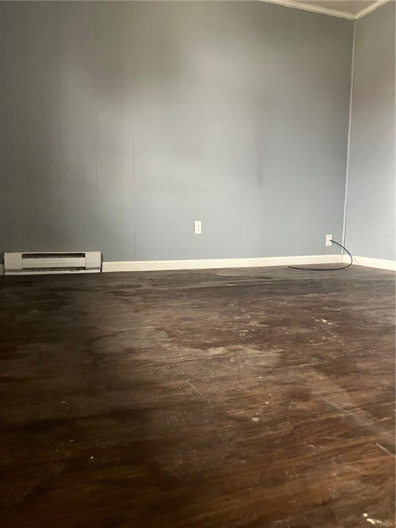 unfurnished room featuring dark hardwood / wood-style floors and a baseboard heating unit