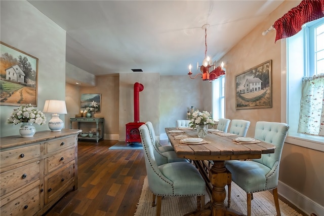 dining area with dark hardwood / wood-style flooring, a wood stove, and an inviting chandelier