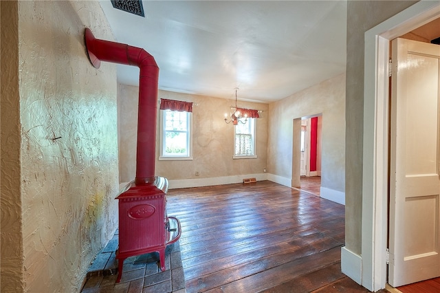 unfurnished room featuring a chandelier, dark hardwood / wood-style flooring, and a wood stove