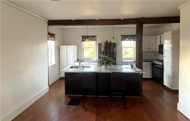 kitchen with beam ceiling, white cabinetry, dark hardwood / wood-style flooring, a kitchen island with sink, and black appliances