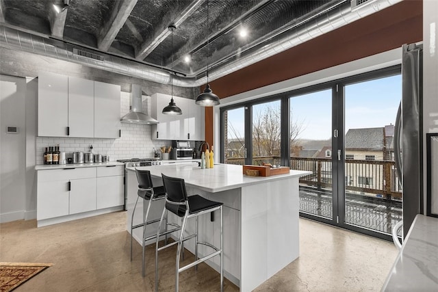 kitchen with pendant lighting, a center island with sink, white cabinetry, and wall chimney exhaust hood