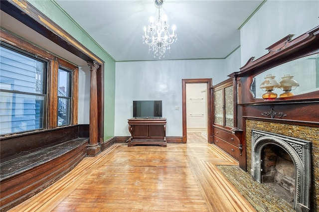 living room with light parquet floors, decorative columns, and an inviting chandelier