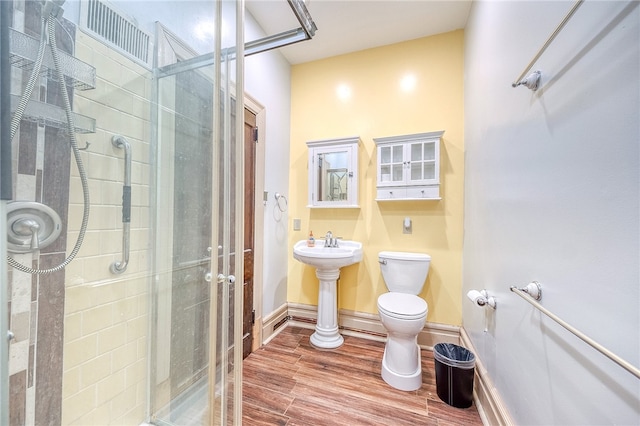 bathroom featuring toilet, sink, hardwood / wood-style floors, and walk in shower