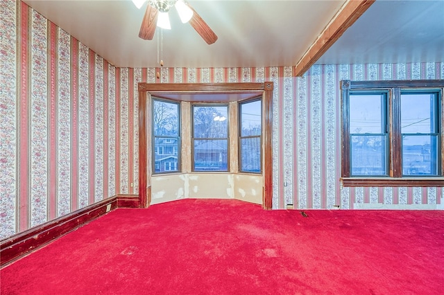 spare room featuring carpet flooring, ceiling fan, and beamed ceiling