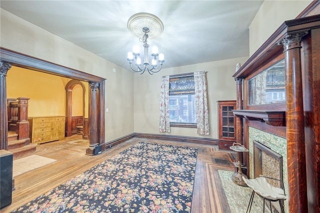 living room with a stone fireplace, wooden walls, an inviting chandelier, and light wood-type flooring