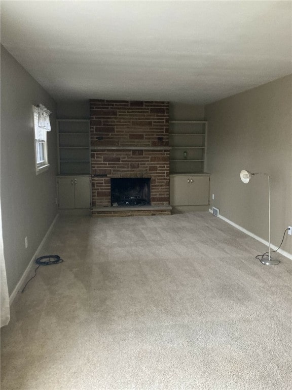 unfurnished living room with a fireplace, carpet, and built in shelves