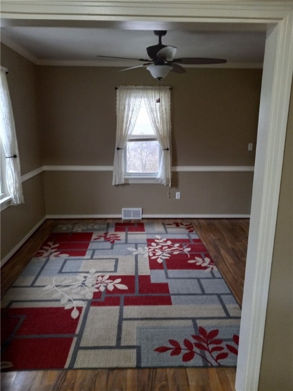 empty room with hardwood / wood-style floors and crown molding