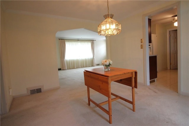 dining area with ceiling fan, light colored carpet, and crown molding