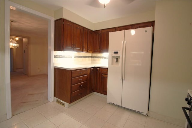 kitchen with tasteful backsplash, light carpet, white fridge with ice dispenser, and an inviting chandelier