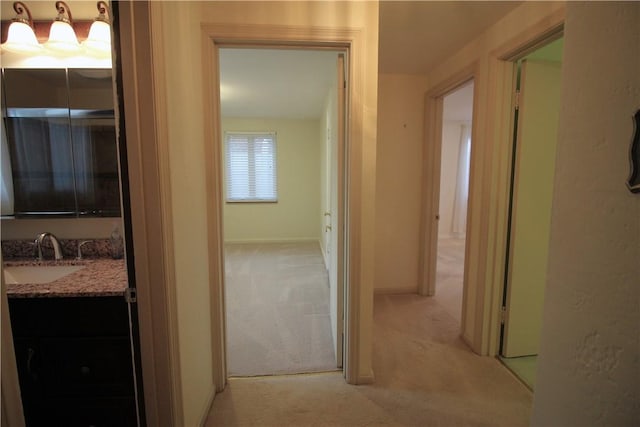 hall featuring light colored carpet and sink