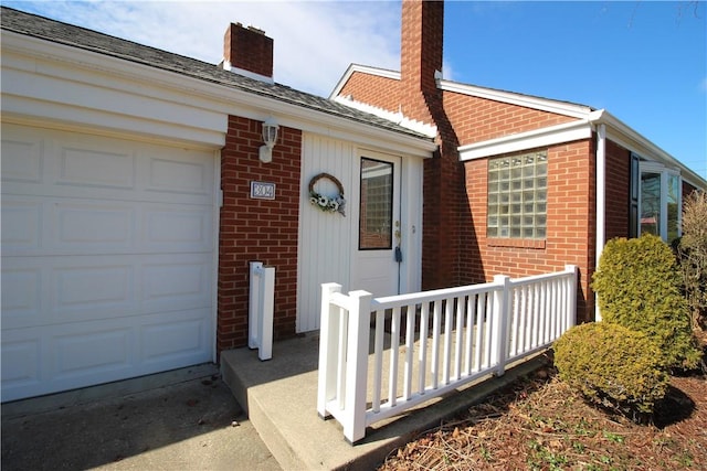 view of front facade featuring brick siding, a chimney, and an attached garage