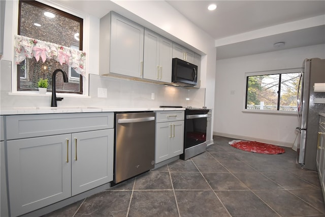 kitchen featuring decorative backsplash, appliances with stainless steel finishes, sink, dark tile patterned flooring, and gray cabinets