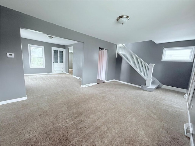 unfurnished living room featuring light colored carpet and a healthy amount of sunlight