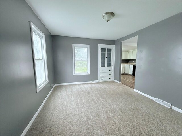 unfurnished room featuring light colored carpet and plenty of natural light