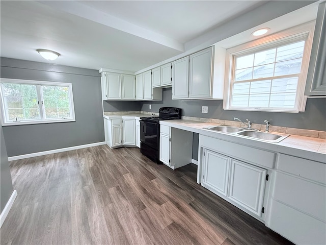 kitchen with sink, dark hardwood / wood-style flooring, white cabinets, and black range with electric cooktop