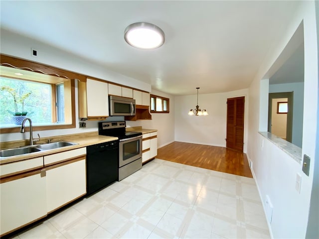 kitchen with sink, stainless steel appliances, an inviting chandelier, decorative light fixtures, and white cabinets