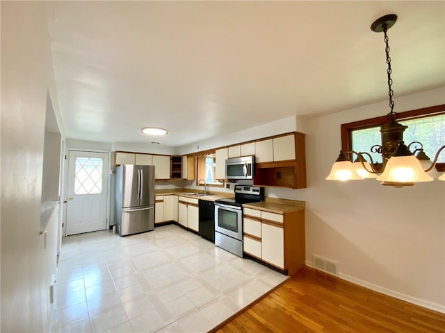 kitchen featuring pendant lighting, plenty of natural light, light hardwood / wood-style floors, and stainless steel appliances